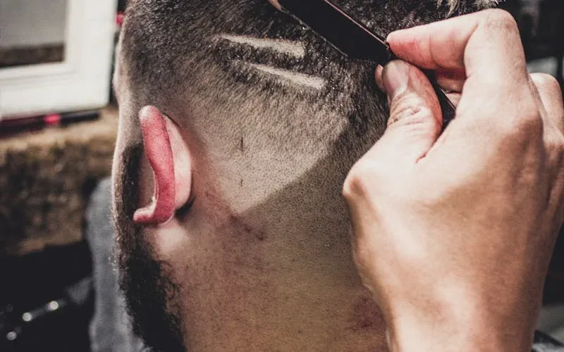 Profissional apresentando combo de serviços em barbearia