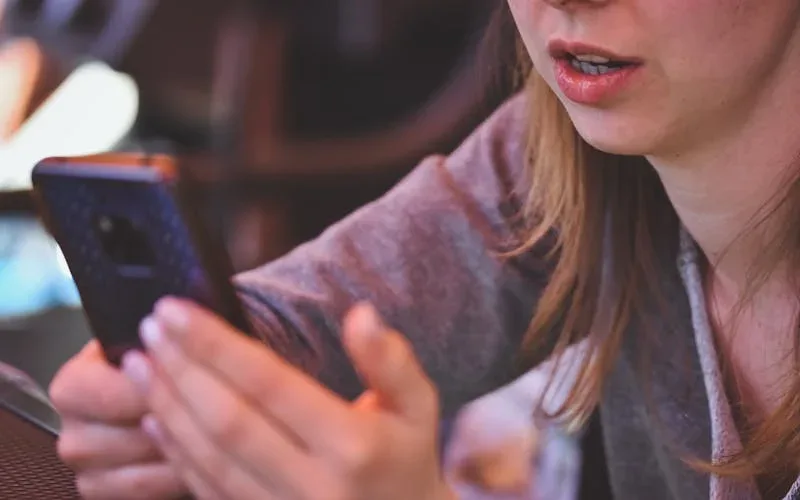 Cabeleireira organizando agenda de atendimentos no celular entre atendimentos no salão